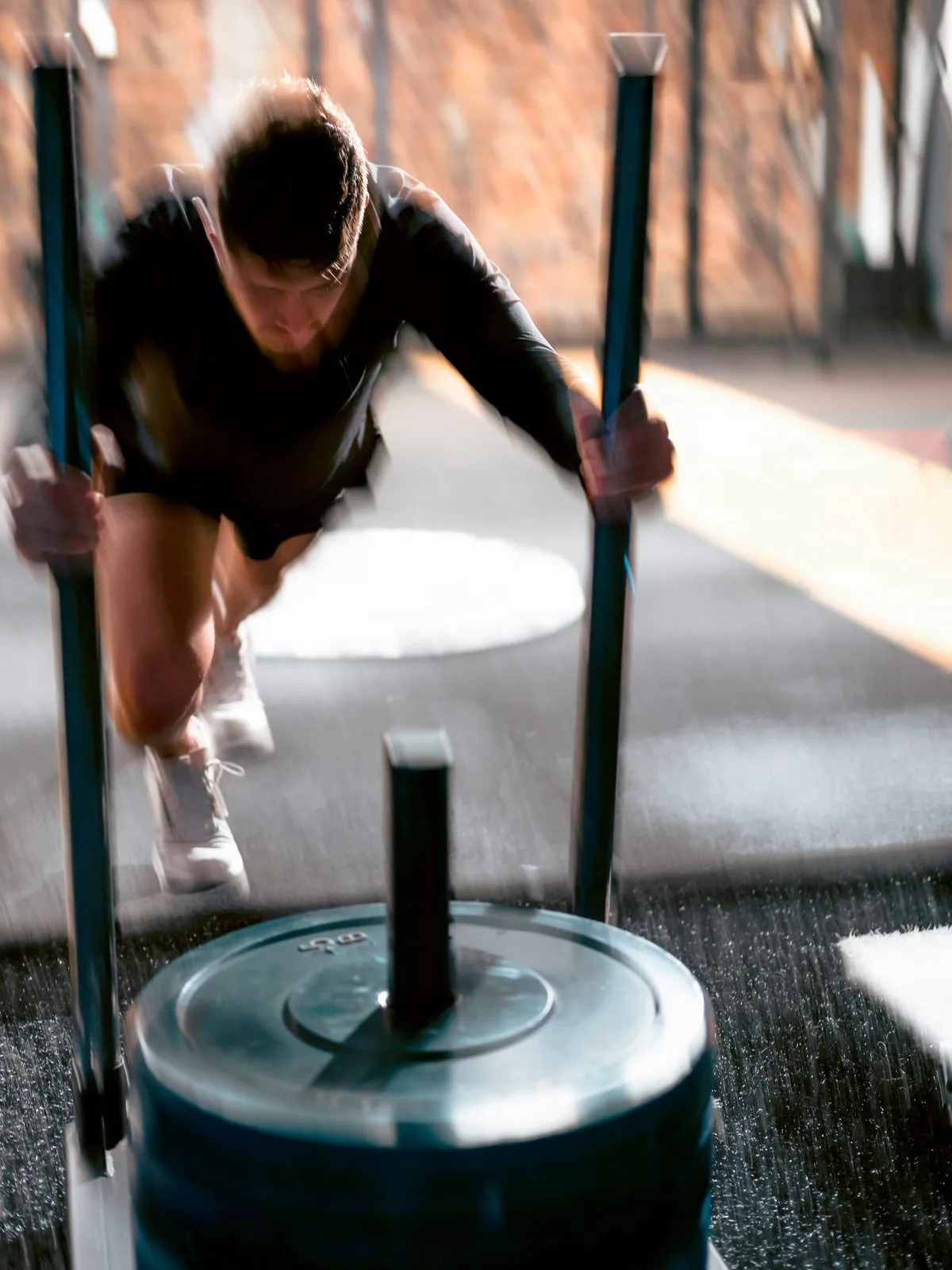 Sportowiec pcha sanki treningowe z obciążeniem na siłowni