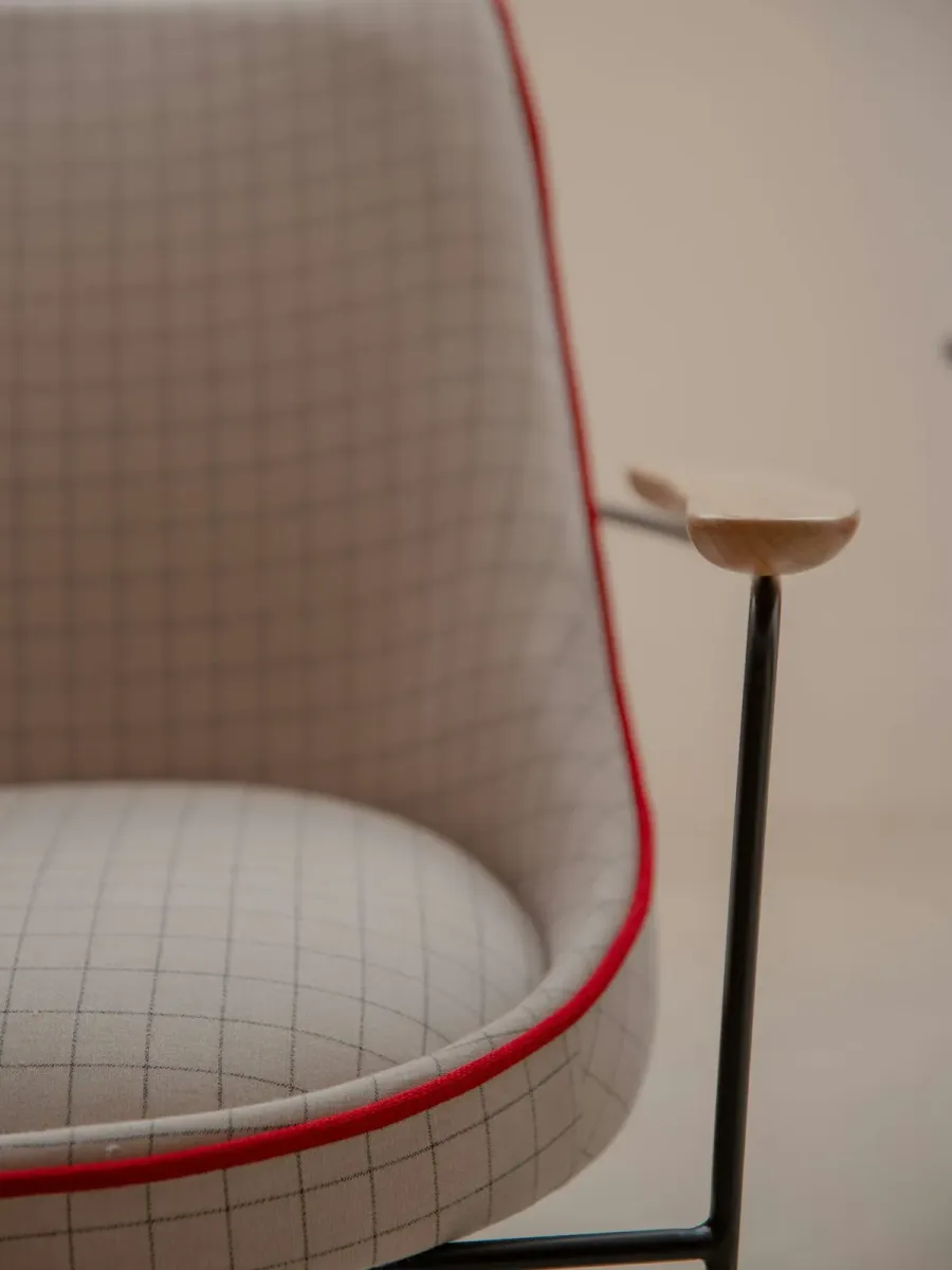 Detal designerskiego fotela w kratę z czerwoną lamówką
