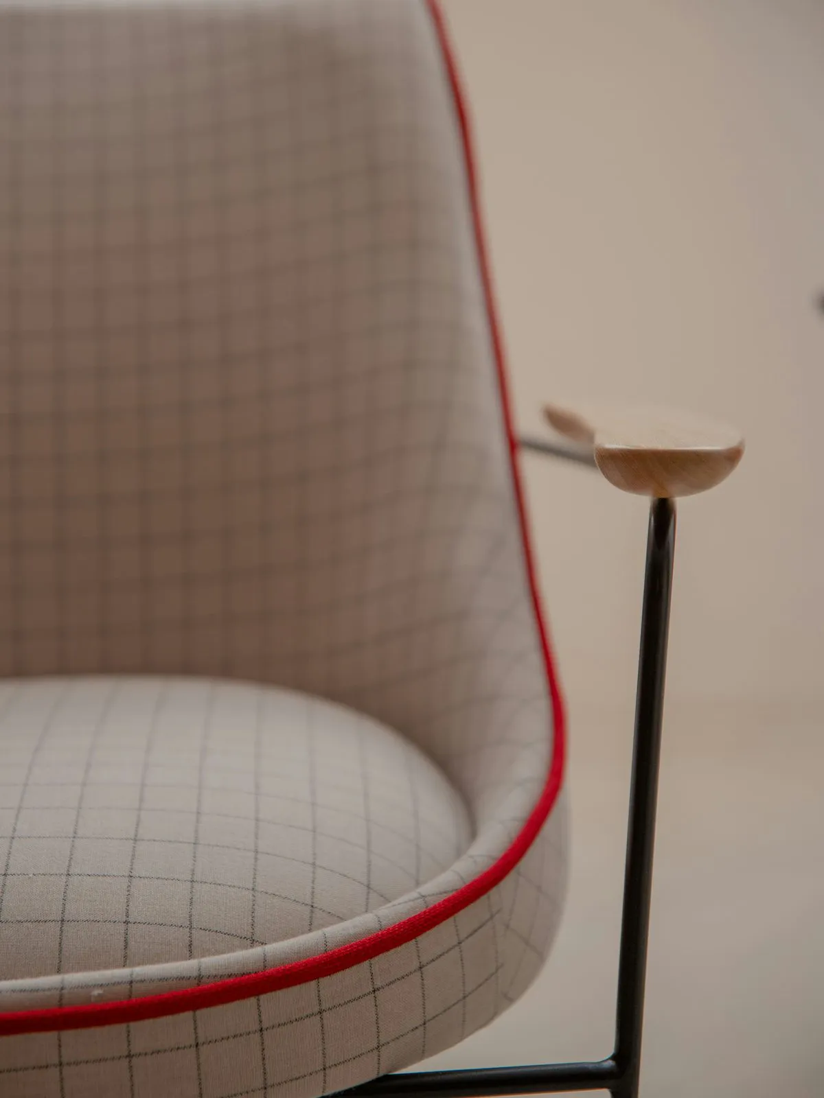 Detal designerskiego fotela w kratę z czerwoną lamówką